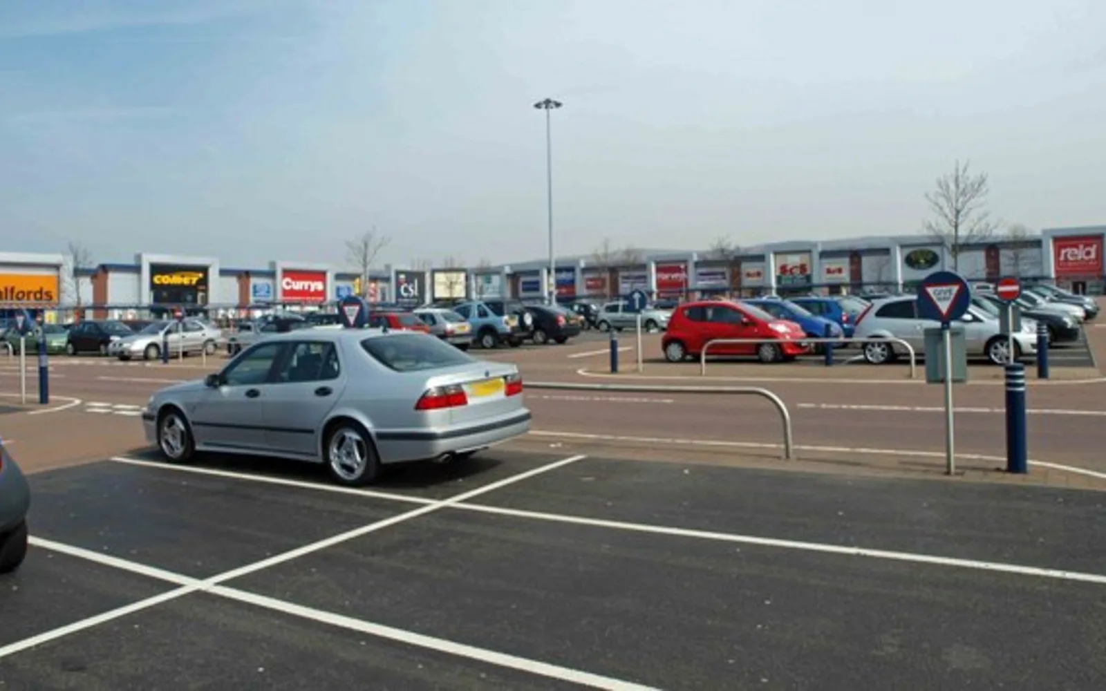 Outdoor parking lot in a shopping center with retail storefronts and directional signage